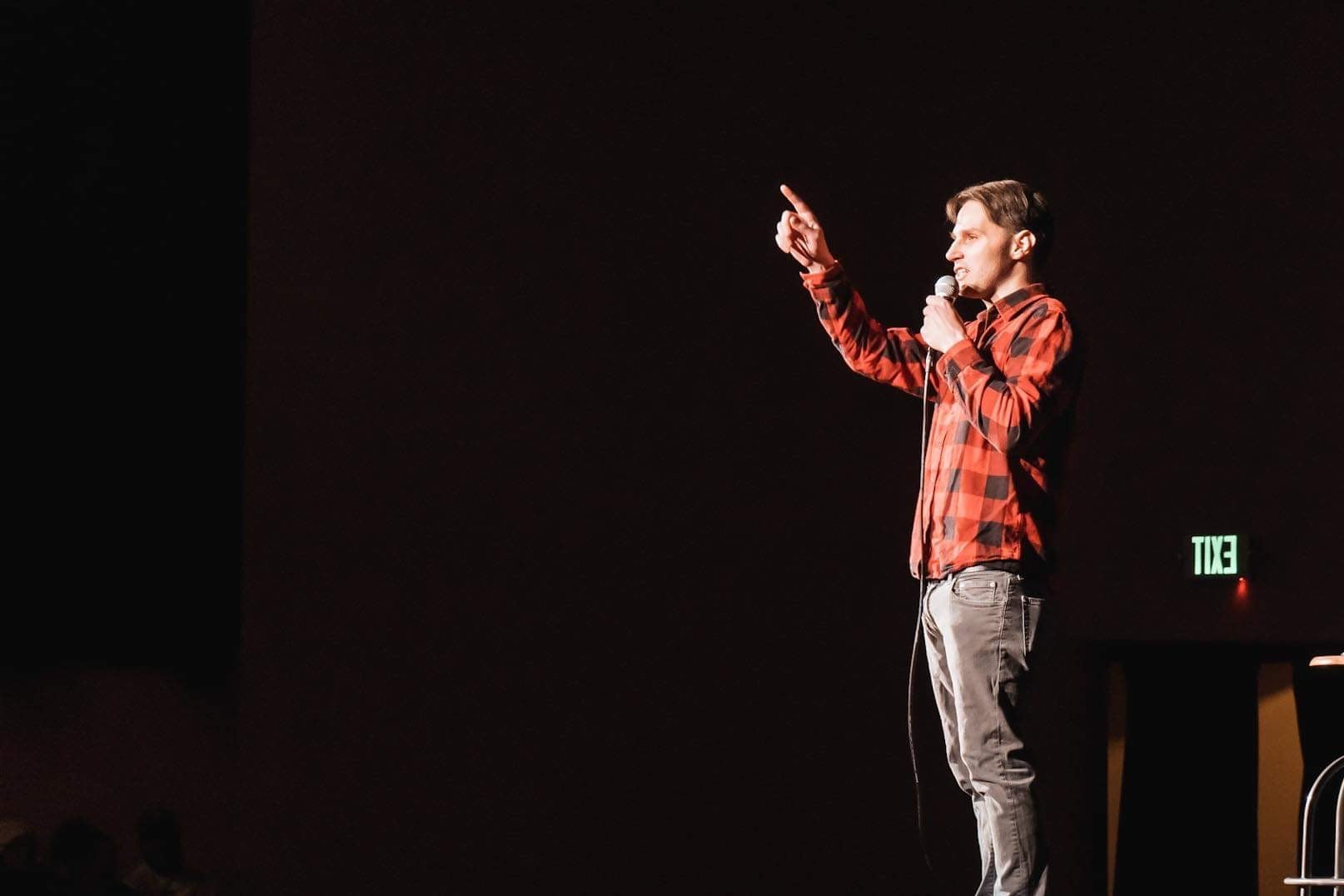 Person on stage with a microphone against a dark background